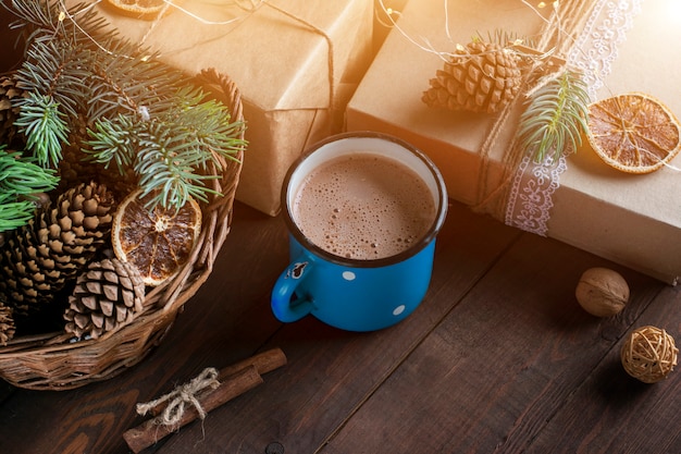 Festive cocoa  in a blue mug on a wooden table with wrapped gifts, decorative elements