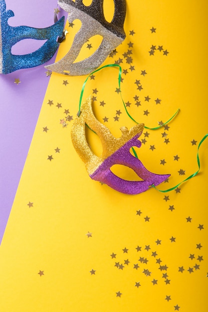 A festive, colorful group of mardi gras or carnivale mask on a yellow purple background. Venetian masks.