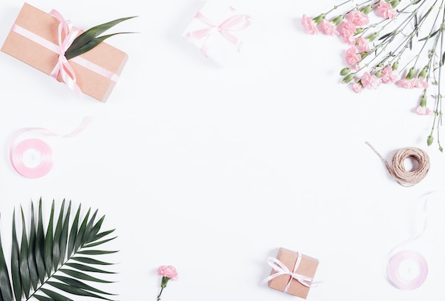 Festive composition: boxes with gifts, ribbons and flowers on white table