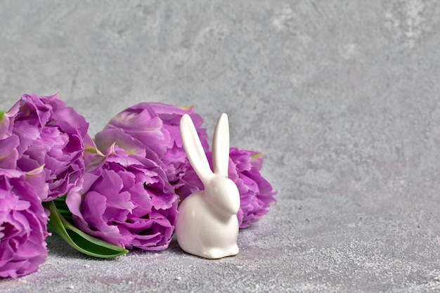 Photo festive composition with purple tulips and ceramic white rabbit