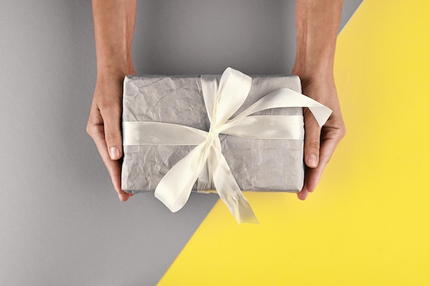 Festive concept gift box in female hands top view Gray and Yellow