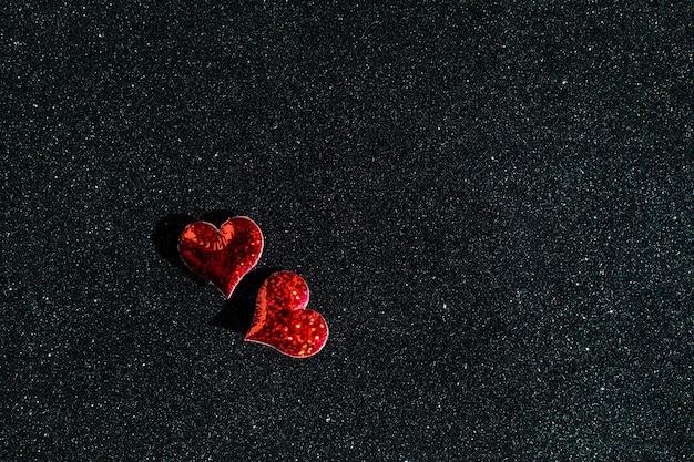 Festive concept of Valentine's Day Little red hearts on the sparkle black background with copy space