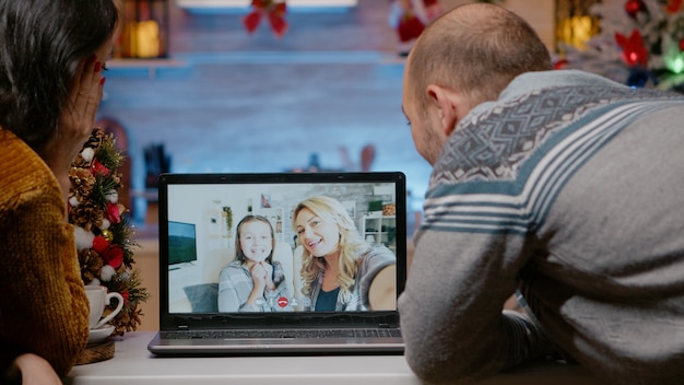 Festive couple talking to family on video call conference