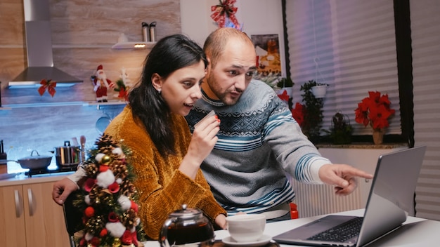 Festive couple using credit card for christmas shopping