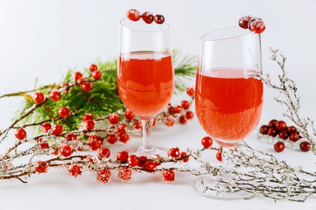 Festive cranberry cocktail with red berries decoration on white surface.