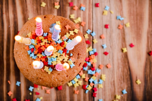 Festive cupcake, sprinkled with decoratings, with lighted candles