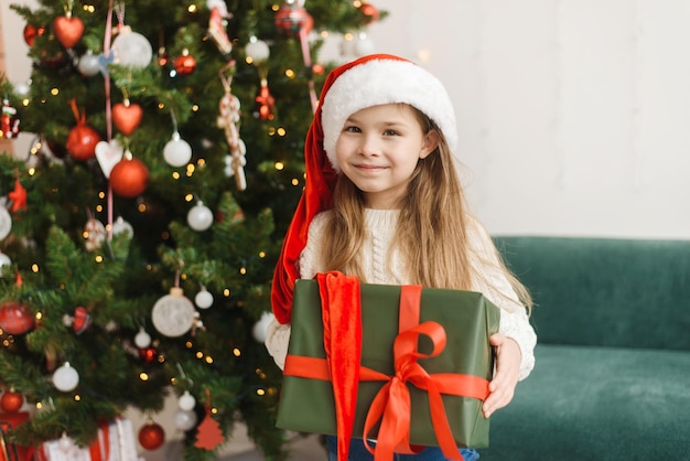 Festive cute little girl opens a gift at home in the living room Christmas and New Year