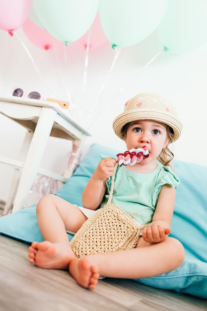 Festive decor for two years toddler birthday girl sitting on the floor eating ice cream