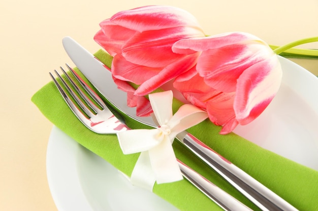 Праздничная сервировка обеденного стола с тюльпанами на бежевом фоне