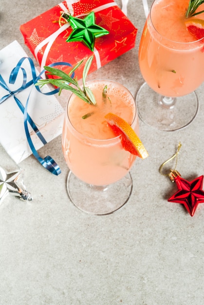 Bevanda festiva per la festa di natale, cocktail mimosa con champagne, pompelmo e rosmarino, su un racconto di pietra,