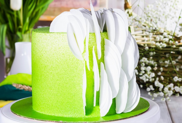 Festive Easter cake with green chocolate white chocolate petals surrounded by spring tulips