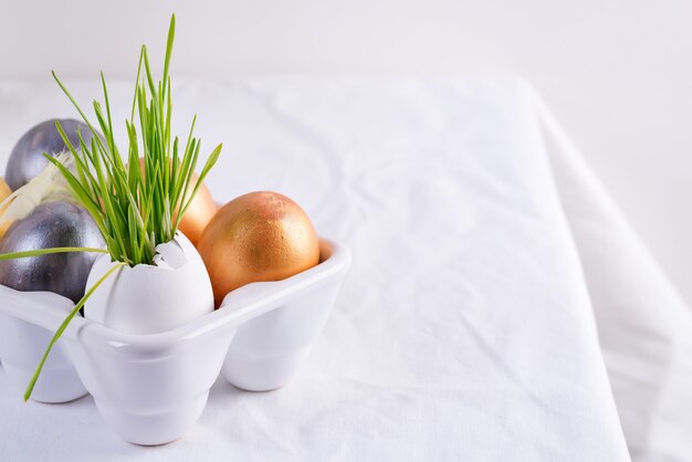 Festive Easter card with homemade painted eggs in a plastic box and fresh green grass on a tablecloth