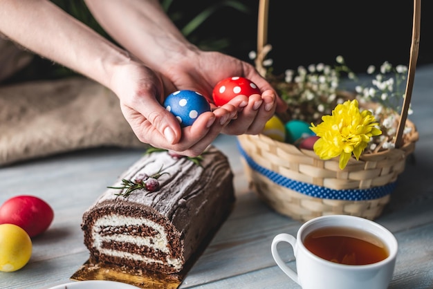 Festive Easter lunch with colorful bright eggs in a basket and an Easter cake on a wooden table Concept of a traditional spring holiday