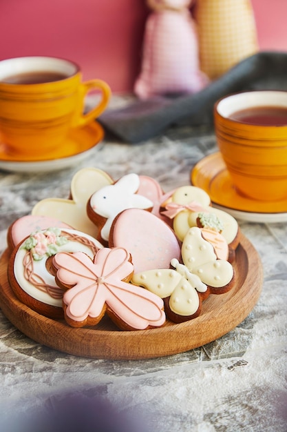 Праздничное пасхальное печенье, чашки чая на украшенном столе, праздничное чаепитие
