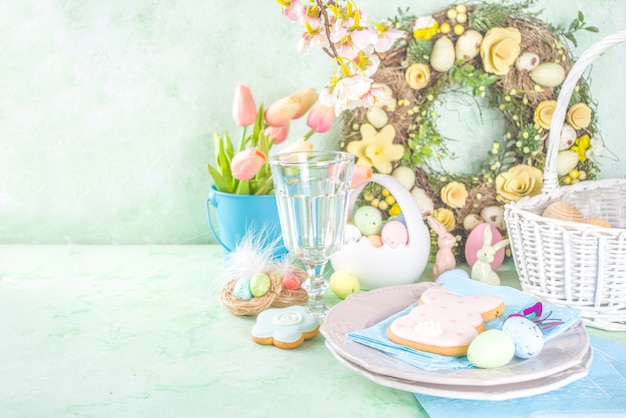 festive easter table setting with traditional spring flowers, easter colorful eggs and sugar cookies