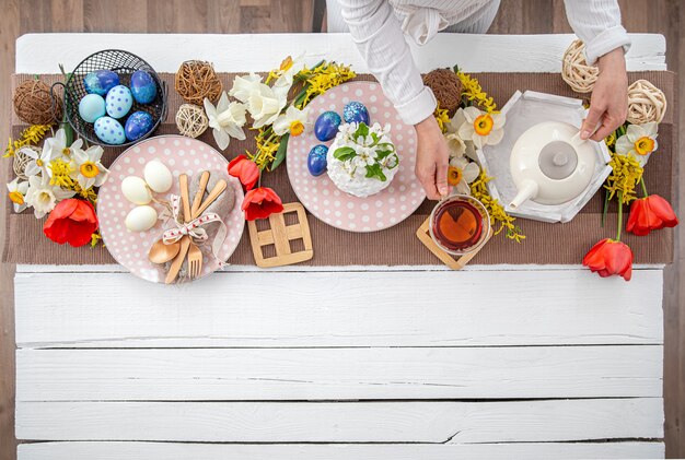 Festive Easter table with homemade Easter cake, tea, flowers and decor details copy space. Family celebration concept.