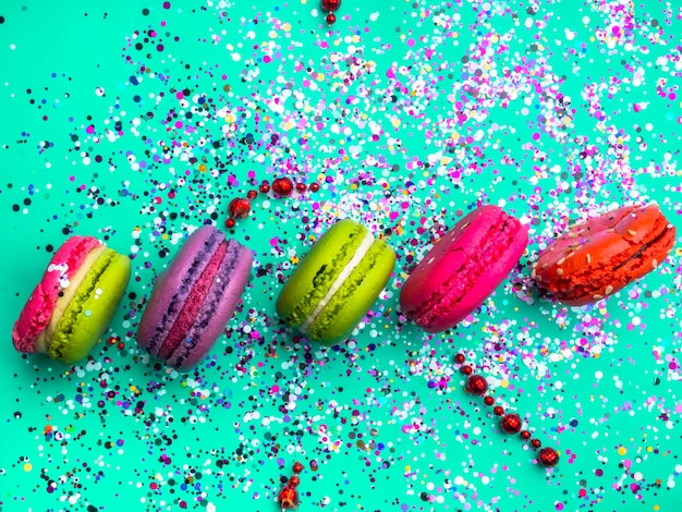 Photo festive flat lay with colorful confetti and macaroons on trendy mint turquoise background holiday concept selective focus