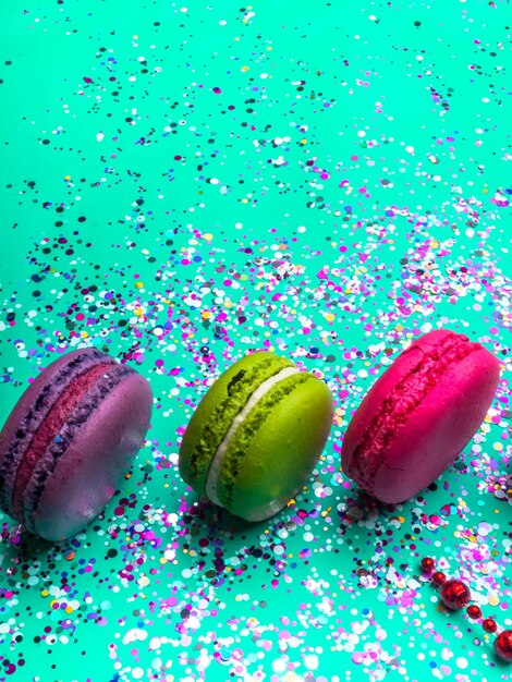 Festive flat lay with colorful confetti and macaroons on trendy mint turquoise background Holiday concept