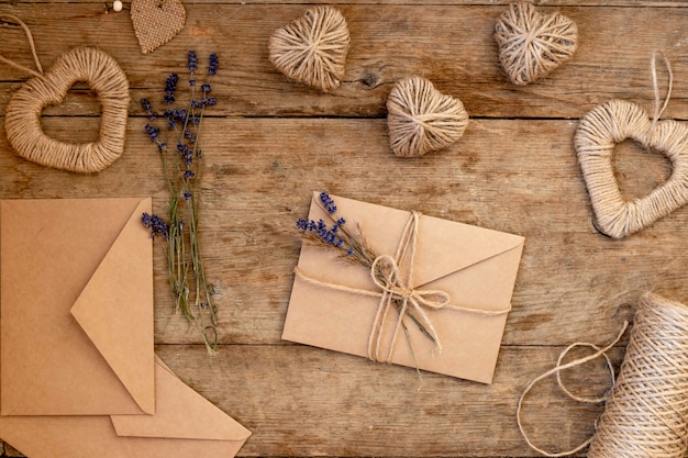 Festive flatly for valentine's day on wooden table. Craft paper beige envelopes decorated with lavender flowers and jute rope. Zero waste Valentine's Day