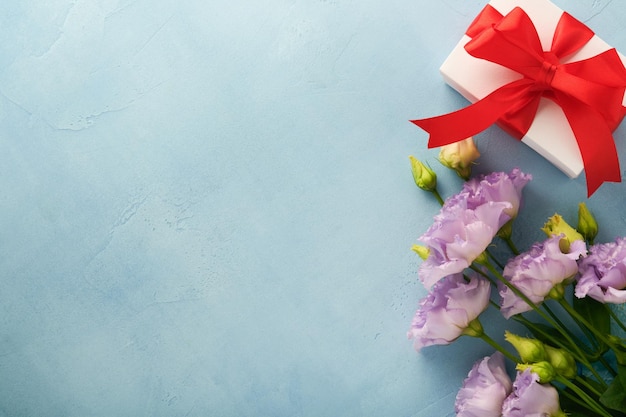 밝은 파란색 콘크리트 배경에 리본이 있는 축제 꽃 구성 보라색 및 선물 상자 어머니의 날 개념 꽃 프레임 오버헤드 뷰 복사 공간이 있는 상위 뷰