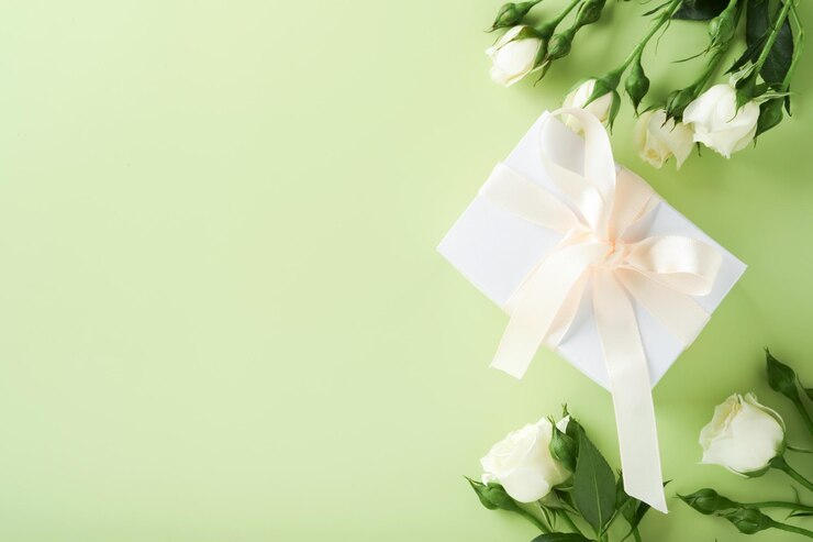 お祝いの花の構成紫色と薄緑色の背景に白いリボンが付いた白いギフトボックス花のフレーム俯瞰図コピースペースのある上面図