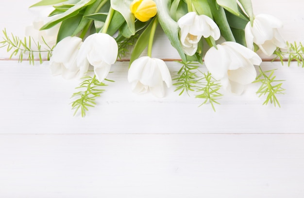 白い木製の机の背景にお祝いの花白いチューリップの構成オーバーヘッド上面図フラットレイコピースペース誕生日母のバレンタイン女性の結婚式の日のコンセプト
