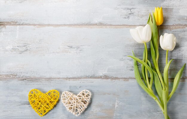 Festive flower white yellow tulips composition handmade heart on blue wooden desk background Overhead top view flat lay Copy space Birthday Mother's Valentines Women's Wedding Day concept