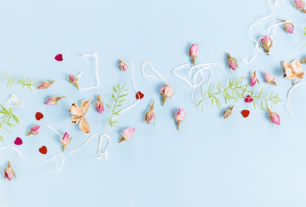 Photo festive flowers composition frame made of dried rose flowers shells ribbon on blue background overhead top view flat lay copy space birthday mothers valentines womens wedding day concept