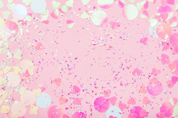 Cornice festosa di coriandoli colorati e scintillii sulla superficie pastello rosa