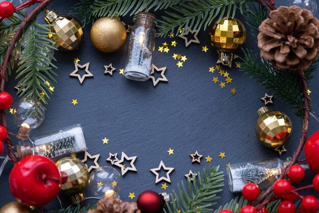 Праздничная рамка с местом для текста темы Рождества и Нового года. Блестки, звезды, гирлянды, конусы, шарики на черном каменном фоне сланца, поздравительная открытка Copyspace