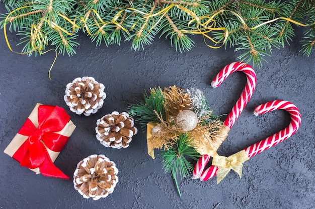 Festive gift box with spruce branches, caramel staves and pinecone on concrete background. The concept of New Year and Christmas. Flatlay. Postcard