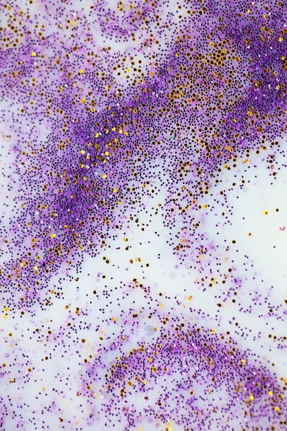 Festive or glamorous background gold and purple sparkles\
scattered on a white background