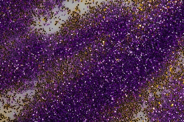 Праздничный или гламурный фон Золотые и фиолетовые блестки разбросаны по белому фону