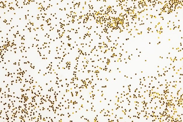 Festive or glamorous background Gold sparkles scattered on a white background