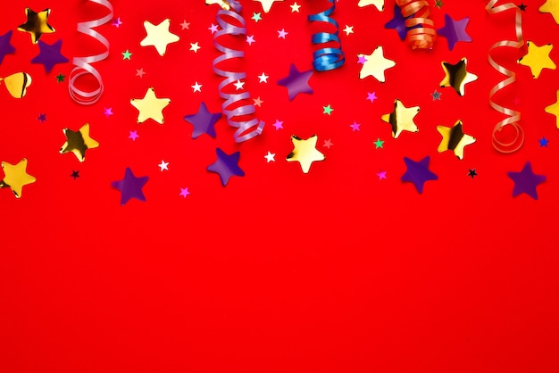Festive stelle dorate e viola di coriandoli su sfondo rosso. spazio per testo o design.