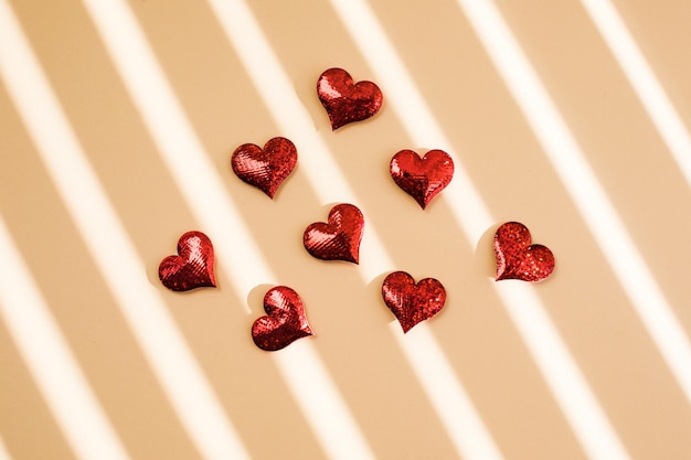 발렌타인 데이를 위한 축제 휴일 인사말 카드 또는 어머니의 날 빨간색 스파클 하트 베이지색 배경에 흩어져 있습니다.