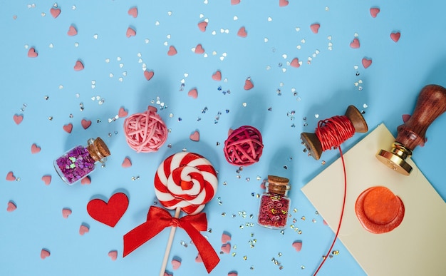 A festive lollipop; letter and gift box lies on a blue background .Concept of love and celebration of Valentine's Day. Top view; flat lay.