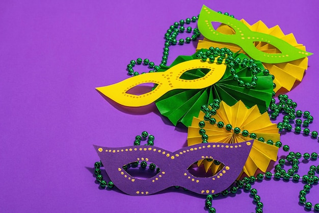 Festive mardi gras masquerade purple background fat tuesday carnival masks beads traditional decor symbolic colors trendy hard light dark shadow flat lay copy space