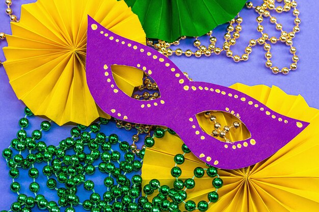 Photo festive mardi gras masquerade violet background fat tuesday carnival masks beads traditional decor symbolic colors trendy hard light dark shadow flat lay top view