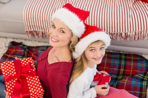 Festive mother and daughter smiling at camera with gifts