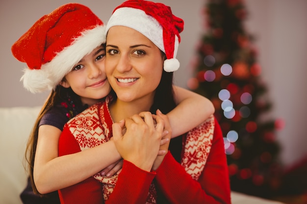 Madre e figlia festive che sorridono alla macchina fotografica