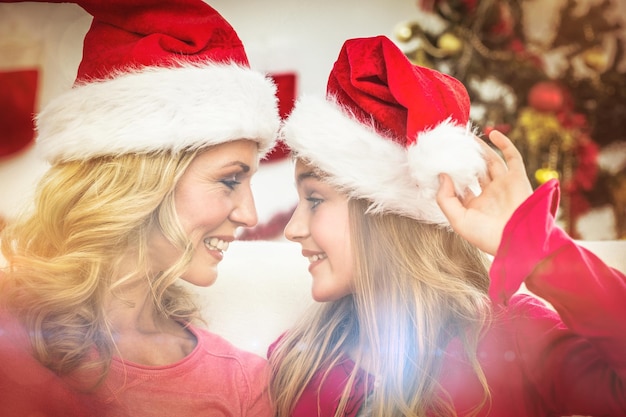 Festive mother and daughter smiling at each other at home in the living room