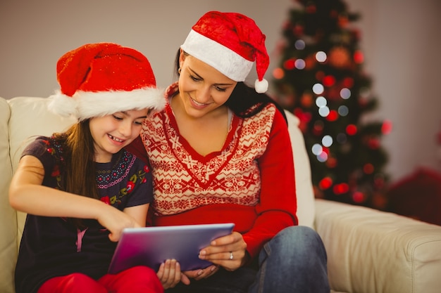 Festive mother and daughter using tablet