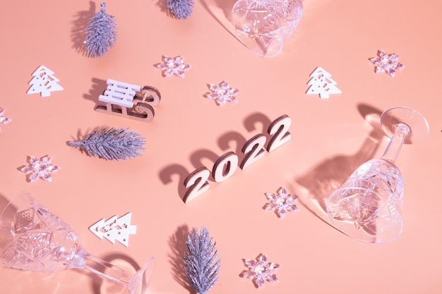 Festive new year flat lay with numbers 2022 and hard shadows with glasses and shiny decor