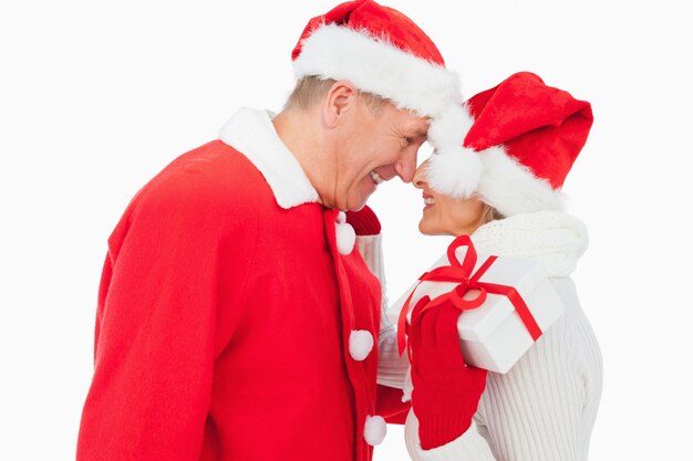 Festive older couple smiling at each other and holding gift