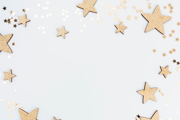 Праздничный пастельный фон. Рождественские звезды и сияющий блеск, конфетти на пастельном фоне. Новогодний фон, плоская планировка.
