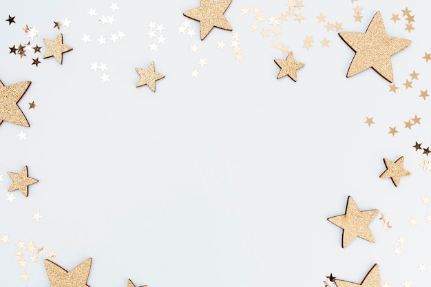 Festive pastel background. Christmas stars and shining glitter, confetti on pastel background. Christmas background, Flat lay.