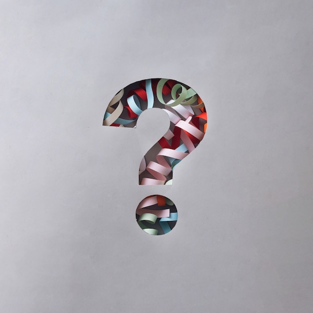 Festive question mark cutout in grey card with twirled party streamers revealed behind with copyspace in a conceptual image