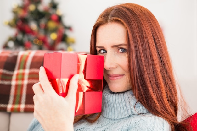 Festive redhead with gift on the couch