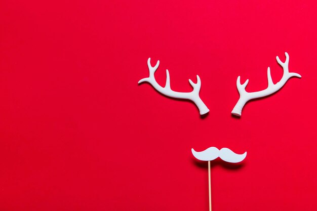 Festive reindeer face made from white antlers and a white moustache on a red background